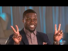 a man sitting in a chair making the peace sign with his hands and wearing a suit