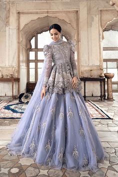 a woman in a blue gown standing on a tile floor with an ornate archway behind her