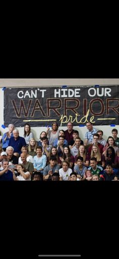 a group of people standing in front of a sign that says can't hide our warrior pride