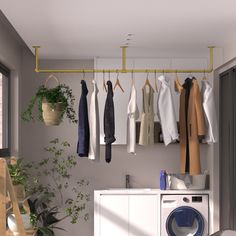 a washer and dryer in a room with clothes hanging on the rack above it