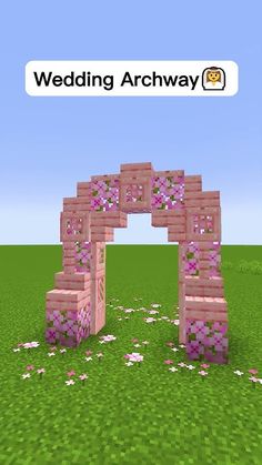 an arch made out of blocks in the middle of a field with flowers on it