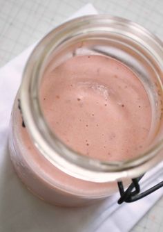 a glass jar filled with pink liquid sitting on top of a white napkin