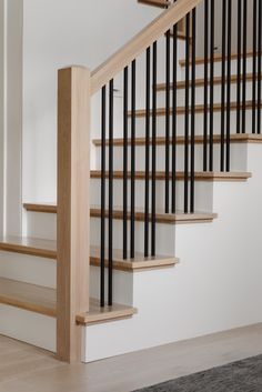 a staircase with black and white railings next to a carpeted floor in an empty room