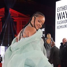 a woman in a green dress walking on a red carpet with other people behind her