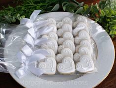 heart shaped cookies are on a plate with white ribbon and greenery in the background