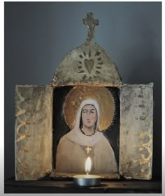 a candle is lit in front of an image of the virgin mary