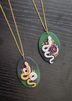 two necklaces with different designs on them sitting on a table next to each other