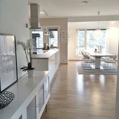 a large open kitchen and dining room with hardwood floors, white walls and flooring