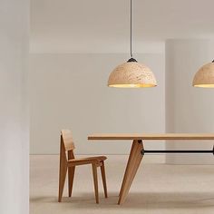 two wooden chairs and a table in an empty room with lights hanging from the ceiling