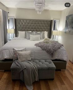 a large bed sitting on top of a hard wood floor next to a chandelier