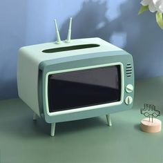 an old fashioned tv sitting on top of a table next to a vase with flowers