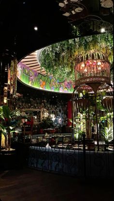 the interior of a restaurant at night with lots of lights and plants on it's walls