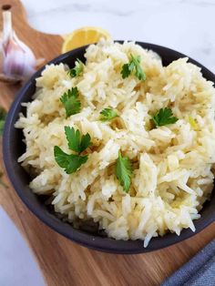 a bowl filled with rice and parsley on top of a wooden cutting board