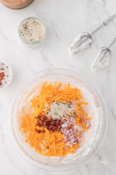 the ingredients to make this salad are in bowls on the counter top, including carrots and cheese