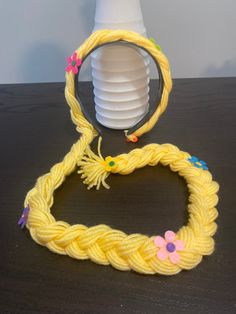 a yellow rope with flowers on it sitting next to a white vase and paper plates