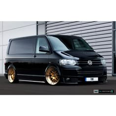 a black van parked in front of a building with gold rims on it's tires