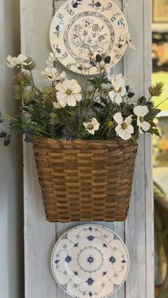 a basket with flowers and plates hanging on a wall