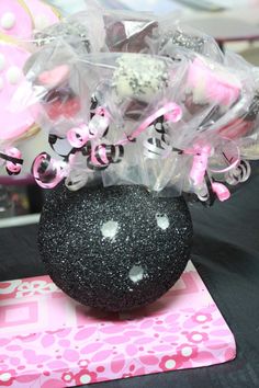 a black cake with pink and white decorations on it's head sitting on a table