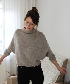 a woman standing in front of a couch with her hands on the back of it