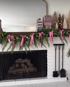 a fireplace decorated for christmas with pink ribbon