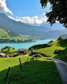 a scenic view of a lake and mountains with houses on the hillside in the foreground