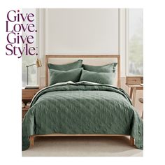 a bed with green comforter and pillows in front of a white wall that says give love, give style