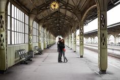 two people standing in the middle of a train station