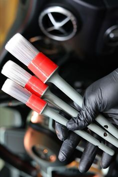 three red and white brushes are held in the palm of someone's hand