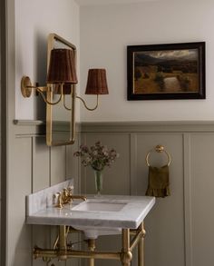 a bathroom sink sitting under a mirror next to a painting