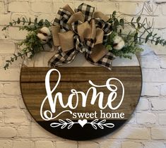 a wooden sign that says home sweet home with a bow hanging on the front door