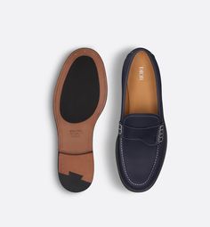 Debuting with the Fall 2024 Collection, the Dior Granville loafer presents a refined version of an urban shoe. Made in deep blue grained calfskin with contrasting topstitching, the style is embellished with a tonal Saddle strap on the vamp. The creation is completed by a leather sole and an engraved Dior signature on the back. The shoe can be worn with any seasonal attire for an elegant and timeless look.. 45 Formal Calf Leather Moccasins With Contrast Sole, Classic Blue Moccasins With Brogue Detailing, Blue Calf Leather Loafers With Rubber Sole, Classic Blue Leather Loafers, Navy Leather Business Loafers, Navy Business Loafers With Rubber Sole, Classic Navy Plain Toe Loafers, Classic Blue Leather Tassel Loafers, Classic Navy Loafers With Leather Sole