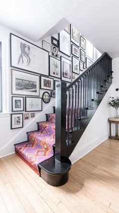 there is a stair case with pictures on the wall and below it, along with an area rug