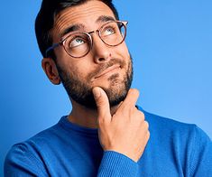 a man wearing glasses is looking up with his hand on his chin and the other hand under his chin