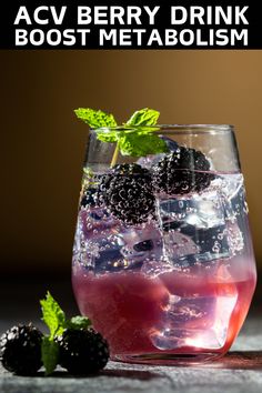 a glass filled with ice and blackberries on top of a table