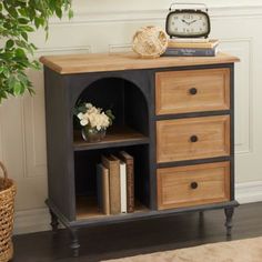 a small wooden cabinet with drawers and a clock on it's side table next to a potted plant