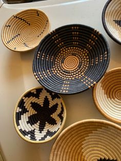 several woven baskets sitting on top of a white counter next to each other in black and brown designs