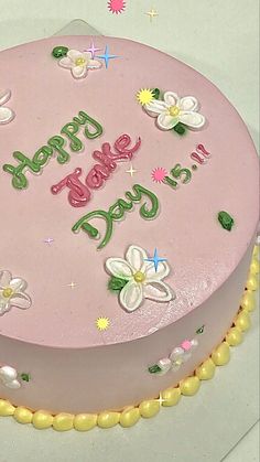 a pink birthday cake with flowers on it