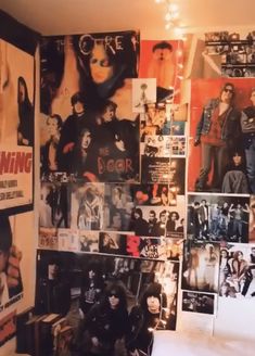 a room filled with posters and pictures on the wall next to a bed in front of a window