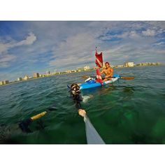 two people in kayaks on the water with buildings in the background and blue sky