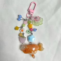 a keychain with various charms attached to it on a white surface, including an orange fish