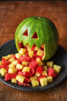 a carved pumpkin is sitting on a plate with chopped fruit in it's mouth