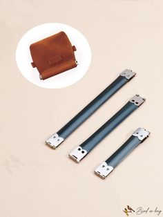 three pieces of leather sitting next to each other on a white surface with metal handles