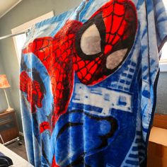 a spiderman shower curtain hanging in a bedroom next to a bed with a lamp on it