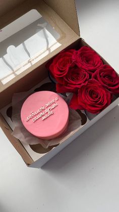 a pink cake in a box with red roses