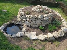 a stone fire pit in the middle of some grass