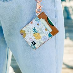 a person wearing blue jeans with a flowered card case attached to their pocket and a metal keychain hanging from the back