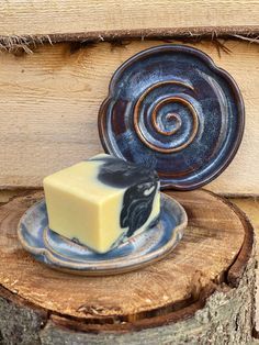 a piece of cheese sitting on top of a blue plate next to a wooden slice