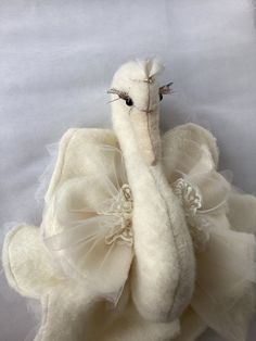 a stuffed swan is sitting on a white sheet