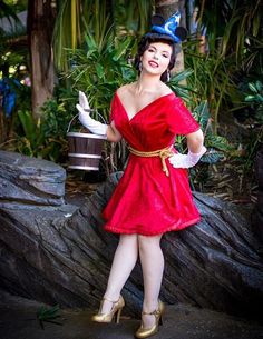 a woman in a red dress and hat posing for a photo with her hands on her hips