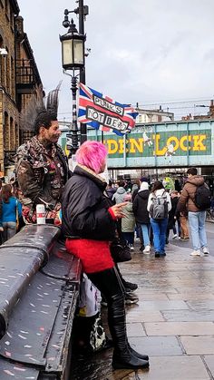 a man and woman sitting on a bench in the middle of a busy city street